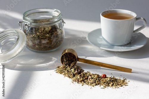 natural tea in a jar and a cup of tea, tea scattered on the table