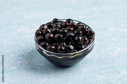 Glass bowl of black tapioca pearl bubbles on the blue background