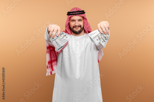 Arab man businessman in national clothes is holding dollars in his hands. Business concept in the middle east, oil sale, investment.