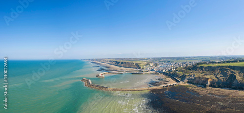 La vue panoramique de la plage, le port et la digue du port en Bessin en France, en Normandie, dans le Calvados, au bord de la Manche.