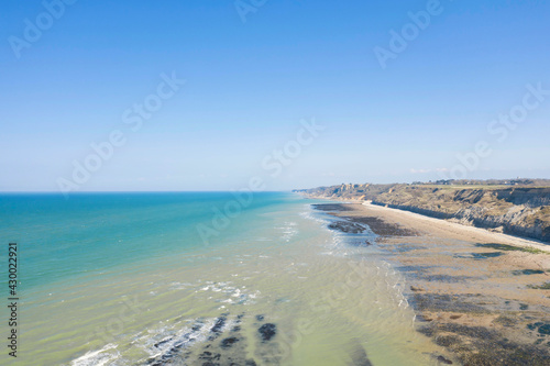 La plage et les falaises du port en Bessin en France, en Normandie, dans le Calvados, au bord de la Manche sous le Soleil.