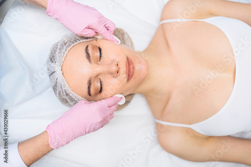 Beautiful happy woman receiving spa treatment. Cosmetologist in beauty salon cleaning woman's face with cosmetic sponges. Facial beauty. Perfect fresh clean skin. Youth and skin care concept 
