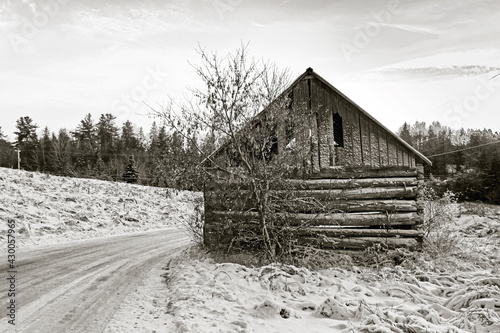 Black and White photo of an old barn by the side of a snow covered road, Quebec, Canada