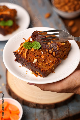 Eating cake piece in hand Carrot and dates cake made dried fruit, raisins, cashew nuts almond. Tasty home made flavored cinnamon , spices Christmas new year Kerala India Sri lanka. Sweet dessert food.