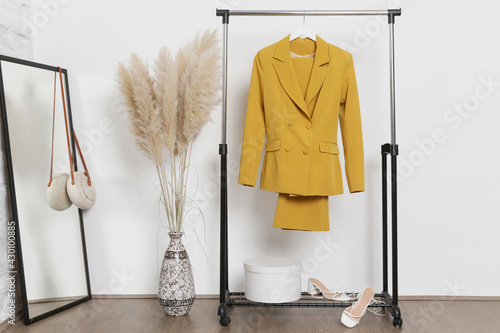 Women's Clothes. Clothes rack, yellow suit and shoes in fashion atelier.