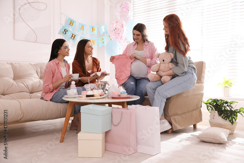 Happy pregnant woman spending time with friends at baby shower party