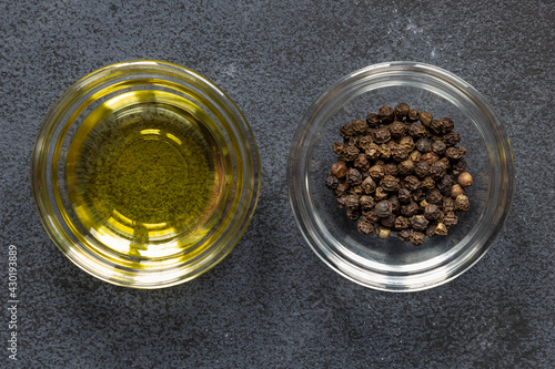 Black papper corn spice and olive oil in bowl on dark background