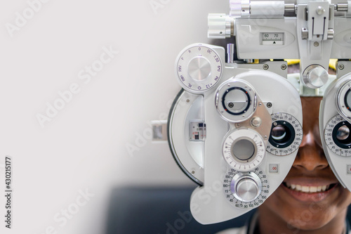 Close-up Of african teen girl Doing Eye Test On Phoropter, African teen girl checking on her eye with optometry machine. copy space background for text