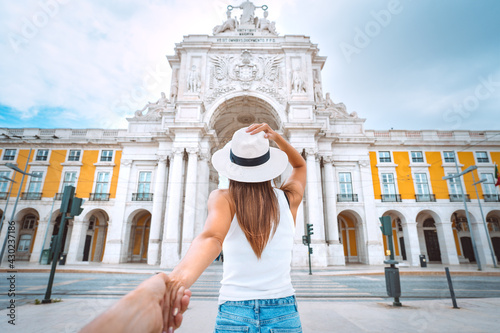 Tourist woman leading man. Follow me. Couple on vacation. Traveling together. Commerce Square with Rua Augusta Arch in in Lisbon, Portugal