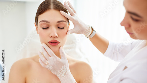 Cosmetologist in gloves checking face of woman