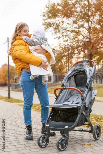 Woman with her cute baby and stroller outdoors