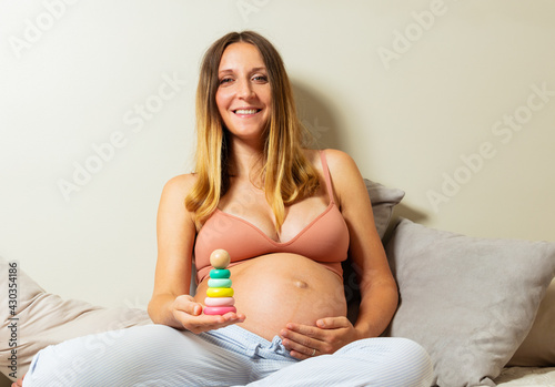 Smiling pregnant woman image holding pyramid toy