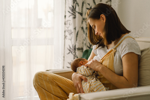 Newborn baby boy sucking milk from mothers breast. Portrait of mom and breastfeeding baby.