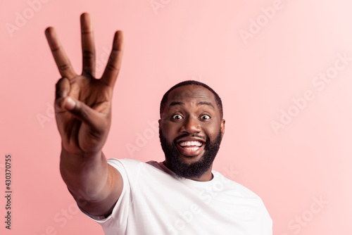 Closeup portrait of young handsome man giving a three fingers sign