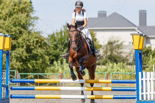 Teen girl jumping horse on her show jumping course