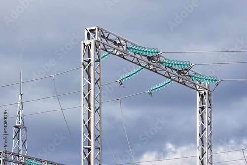 High voltage electric glass insulator of electric high voltage electric transmission power tower and lightning protection mast over cloudy stormy dark sky.