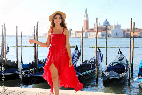 Portrait of young woman in red dress walking in Venice, Italy. Smiling girl posing in Venice, Italy.