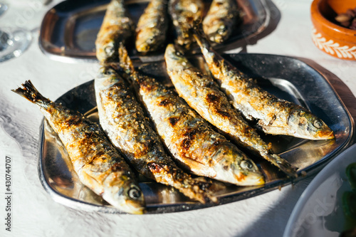 Traditional Portuguese grilled sardines on the metal plate.