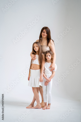 Mom and daughters pose in a white photo studio.