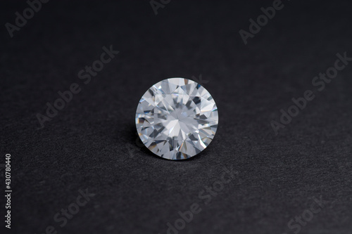 Round diamond faceted cubic zirconia, cubic crystalline form of zirconium dioxide (ZrO2) colorless synthesized material. White synthetic gemstone. Diamond imitation. Black isolated background.