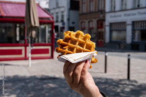 Eating of Belgian sugar waffles, street food in Bruges