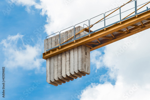 A counterweight of concrete blocks on the tail of a tower crane industrial equipment against a blue sky. Close-up