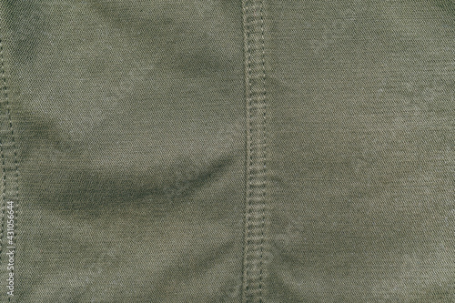 Old used dark green military cotton fabric texture, grunge, rough, dirty background. Sun bleached or faded color