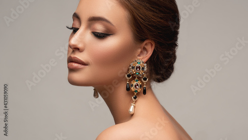 Beautiful woman with long big earrings. Beauty girl with elegant hairstyle and evening make-up. Makeup, cosmetics and jewelry