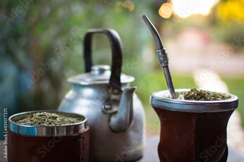 mate tradicional argentino, con una pava de acero, recipiente con yerba mate sobre la mesa, compartiendo un buen mate caliente y respirando aire puro rodeado de naturaleza, alaire libre