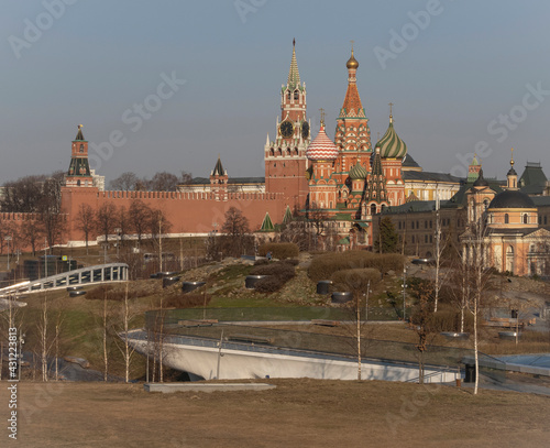 View of the Moscow Kremlin from Zaryadye Park. Early morning. St. Basil's Cathedral and the tower with chimes. Young trees and shrubs. Old church