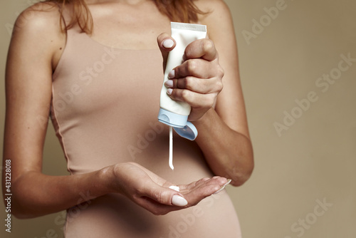 Young beautiful woman with bronze tan holding body lotion or oil. Natural moisturizing cosmetics concept. Mock up