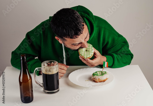 Un hombre soltero desayunando donuts con cerveza negra para celebrar el día de san patricio