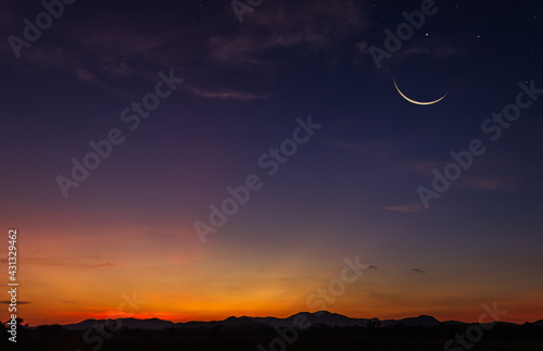 Crescent moon sky on dark blue dusk in the evening with sunset and beautiful sunlight on dark cloud, symbols of Islamic religion in Ramadan