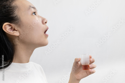 Asian child girl gargling with an antiseptic,protect against the Coronavirus COVID-19 in throat,disinfection prevention of oral wound infections or bad breath,halitosis disease,gingivitis,tonsillitis