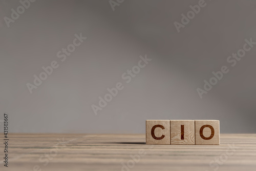 Wood cubes with acronym 'CIO' - 'Chief Information Officer' on a beautiful wooden table, studio background. Business concept and copy space.