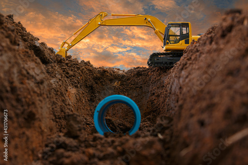 Crawler excavator is digging in the construction site pipeline work on sunset sky background