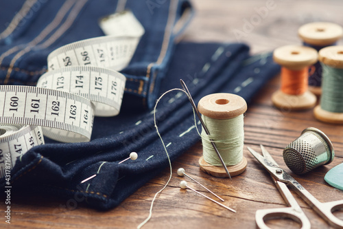 Shortening jeans. Measuring tape, scissors, spools of thread, thimble, including pins and chalk. Jeans cutting.