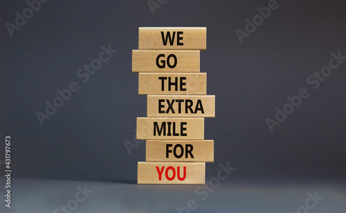 Go the extra mile symbol. Wooden blocks with words 'We go the extra mile for you'. Beautiful grey background. Business, motivational and go the extra mile concept. Copy space.