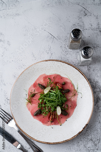 Gourmet appetizer fresh tuna carpaccio on a gray stone table, light, white minimalist photo