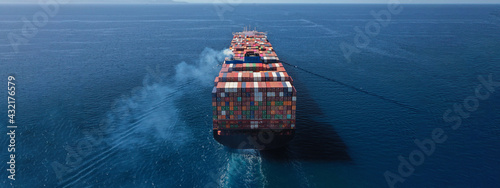 Aerial drone ultra wide photo above huge colourful container carrier vessel cruising deep blue open ocean sea