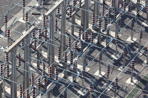 An aerial view taken from a helicopter of a high voltage power distribution substation in Britain. The DNO site has many insulator posts, bus bars and switches all seen from an elevated perspective.