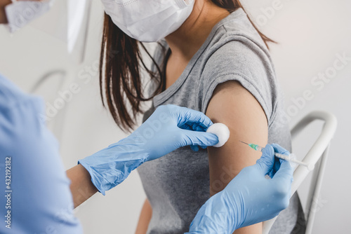 People getting a vaccination to prevent pandemic concept. Woman in medical face mask receiving a dose of immunization coronavirus vaccine from a nurse at the medical center hospital