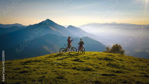 Two females on mountain bikes talking and looking at beautiful sunset