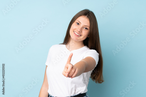 Teenager caucasian girl isolated on blue background showing and lifting a finger
