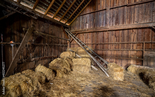 An old orchard ladder and several bales of hay inside an old abandoned barn near Jefferson Oregon.