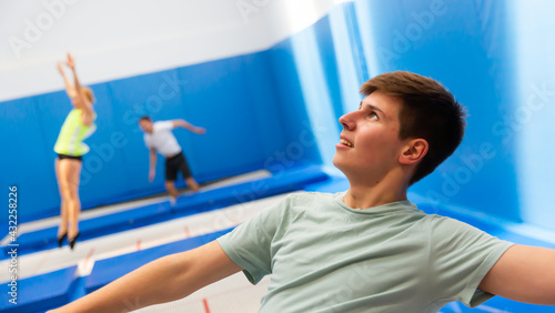 Close up portrait of teenager boy training jumping movements during trampoline workout