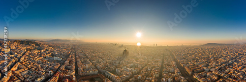 Aerial panorama drone shot of skyline in Barcelona city center in foggy sunrise golden hour in Spain winter