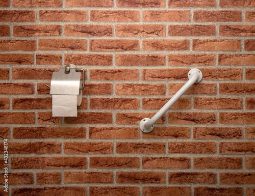 Bathroom detail. Toalet paper holder and handrail on a brick-shaped wall