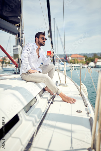 A young man is enjoying a coffee while sitting on a yacht at sea. Summer, sea, vacation