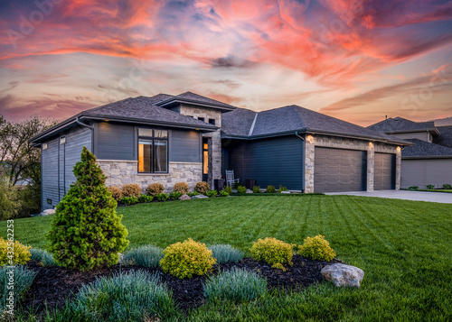 Luxury home during twilight golden hour with pink and purple sky and lush landscaping in Nebraska USA